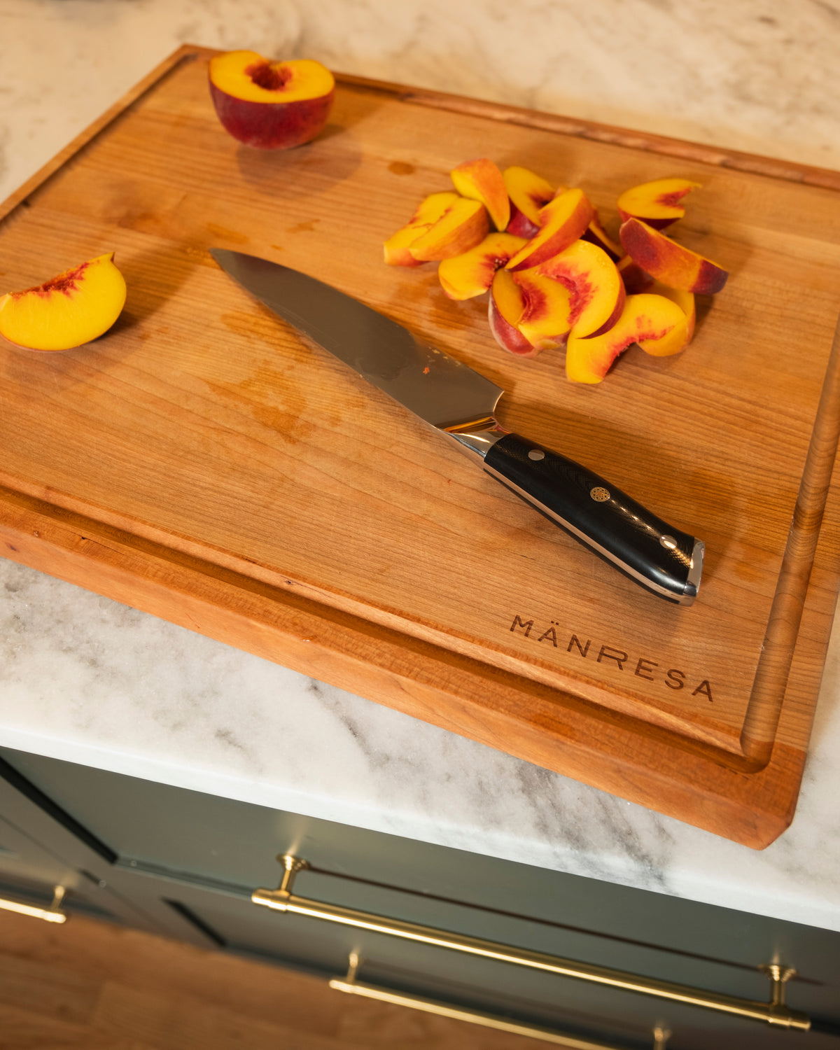 Sliced peaches and a chef knife on a wood butcher block