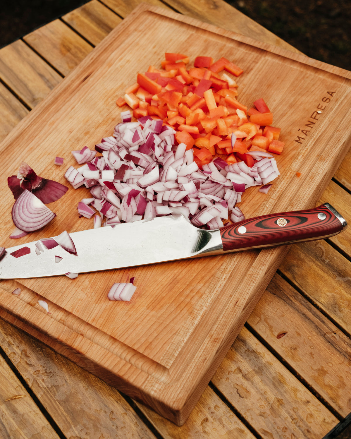 Mänresa American Pro chef knife on a Mänresa butcher block with chopped red onion and red pepper