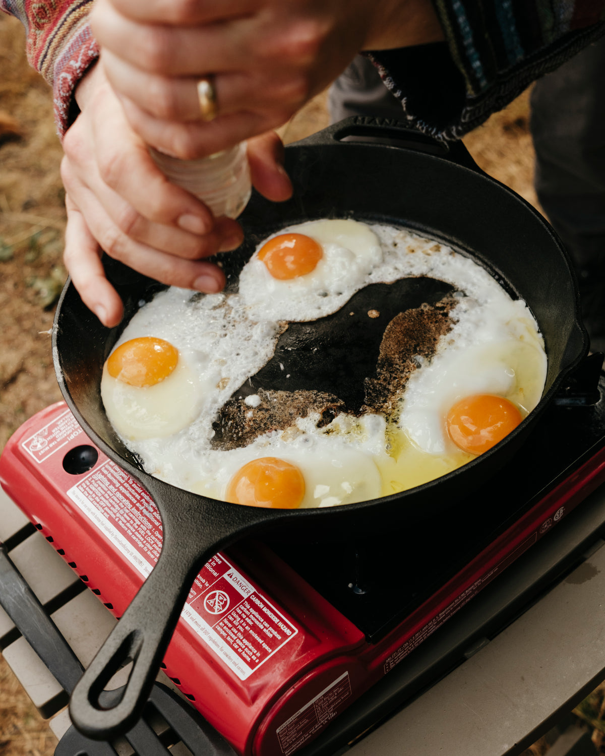 Eggs frying in a cast-iron pan on a camp stove